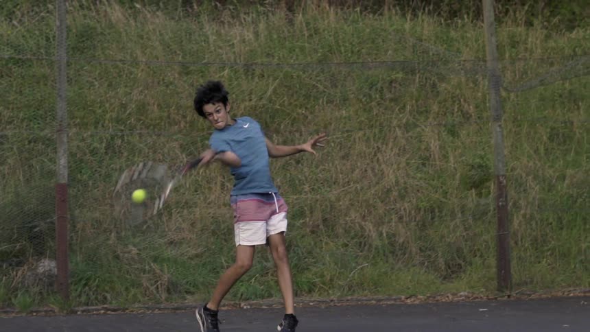 Outdoor Tennis Action With Kid Playing on Court During Sunny Day Match.