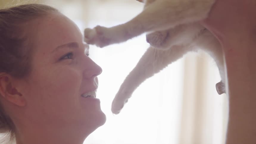 A woman is picking up her cat