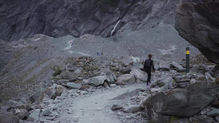 A woman walks through a rocky area in the wilderness