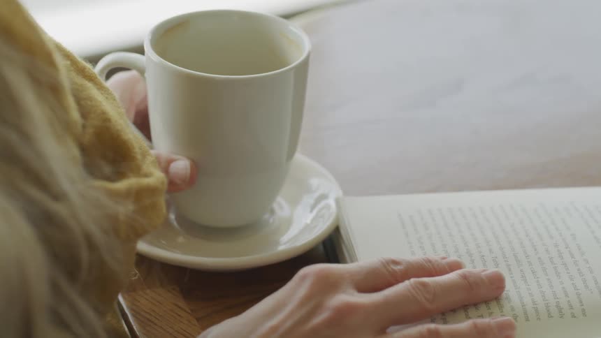 Girl reading a book while sipping coffee
