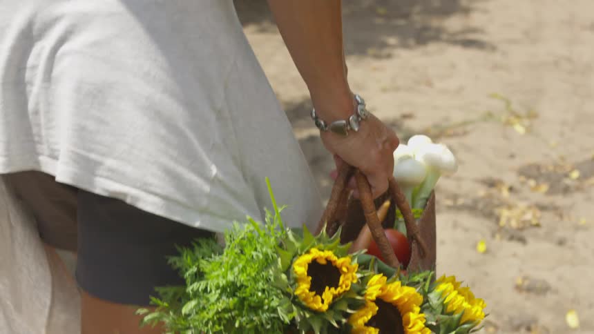 A woman carries a basket with flowers in it