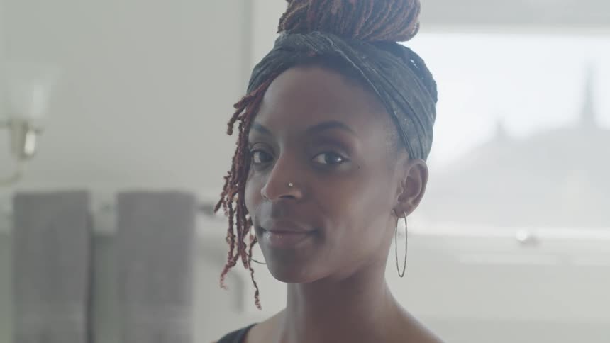 A woman with a nose ring and hoop earrings looks at the camera