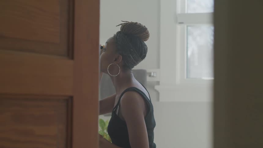 A woman applies makeup while standing in front of a bathroom mirror