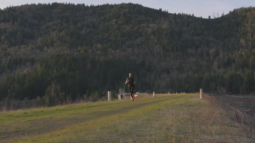 A woman runs through a path near tall hills