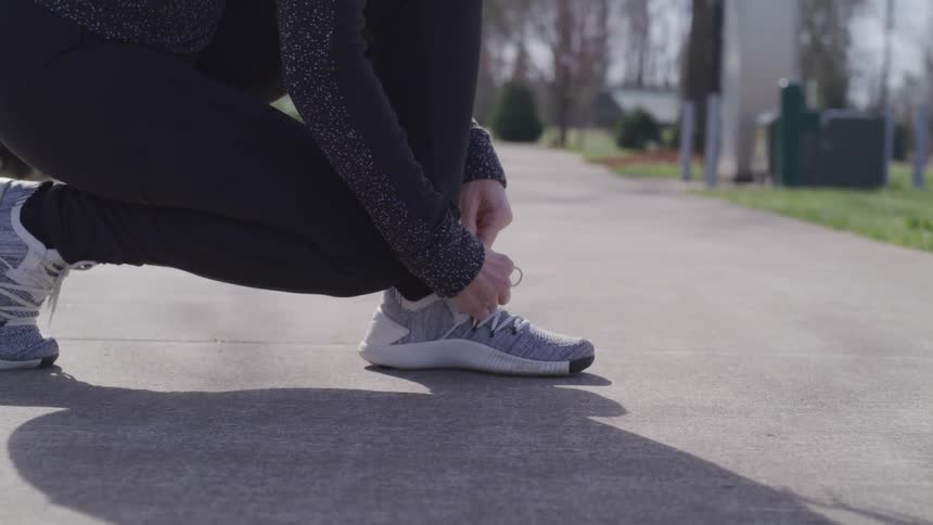 A woman ties her shoes outside