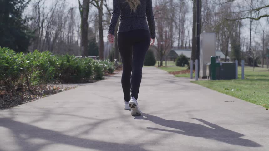 Blonde woman walks in a public park on a sunny day