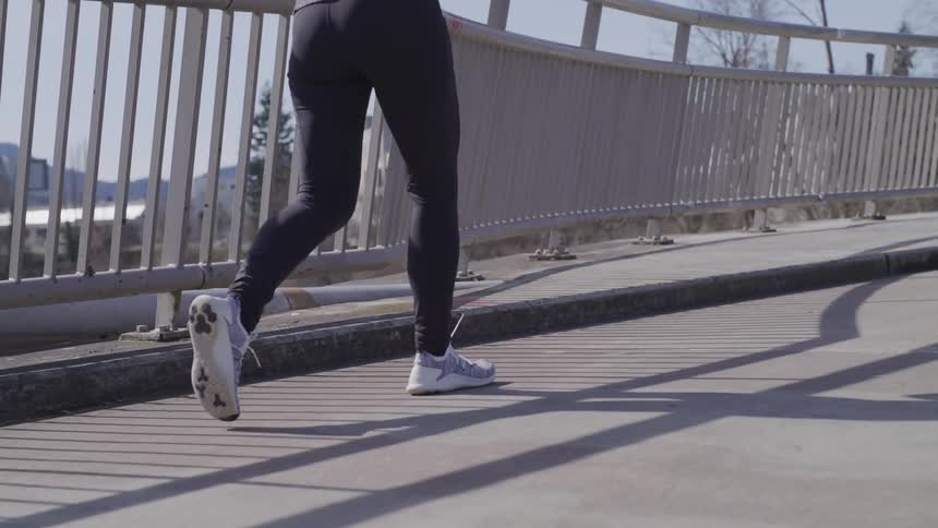 Womans legs walking on the pavement next to railing