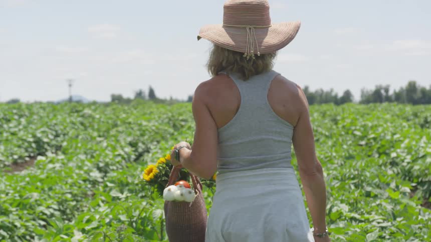 A woman is in a rural farm area holding a basket