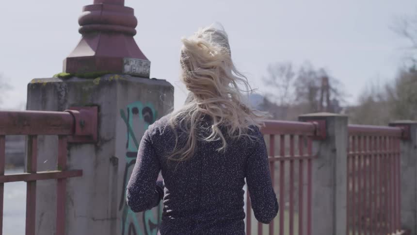 Woman with blonde hair jogging at the bridge