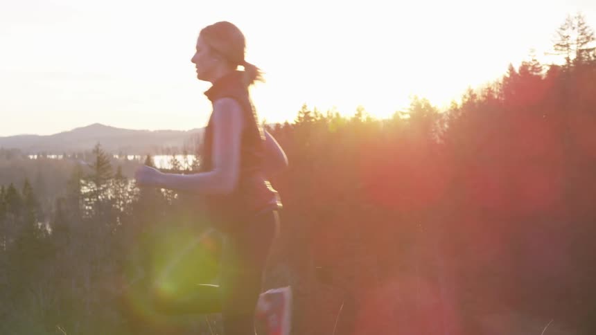 Blonde woman runs in the forest while the sun goes down