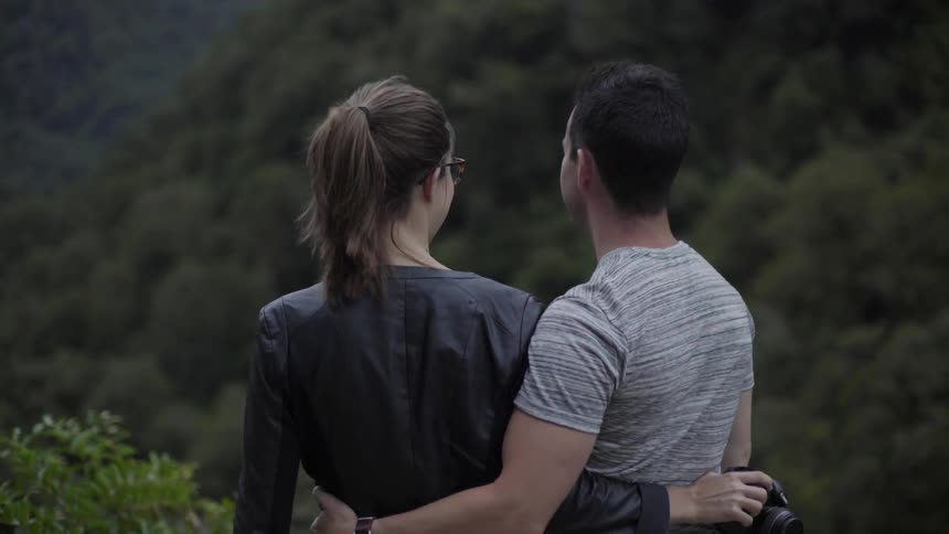 A man and woman standing with their arms around each other as they smile and talk
