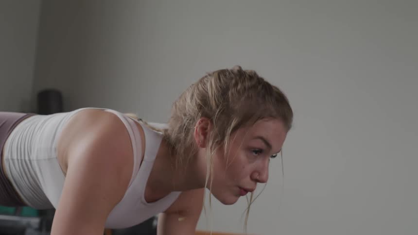 Blonde woman does plank in the gym during daylight