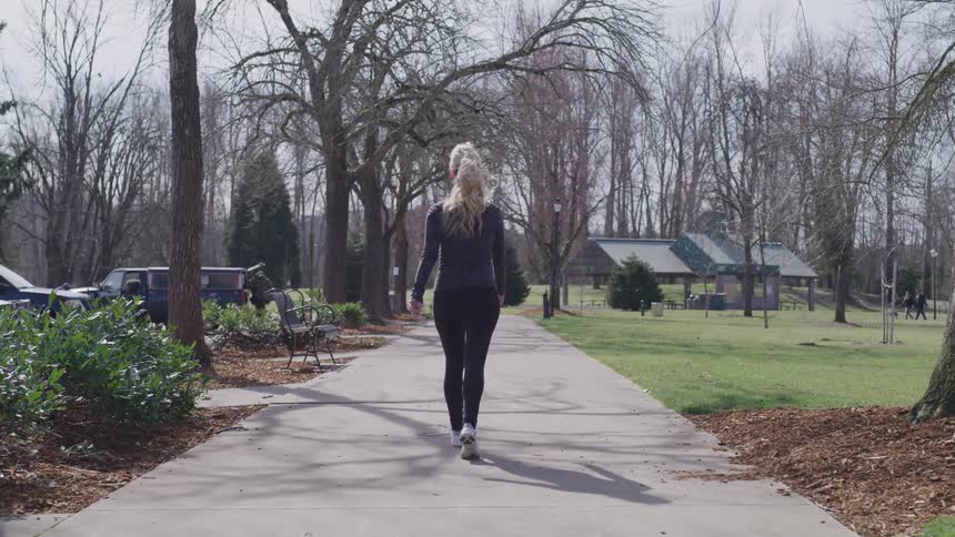 A woman walking down a pathway in a park