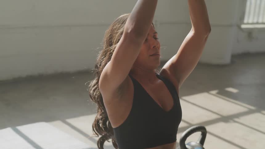 Brunette female with long hair working out with kettle bells