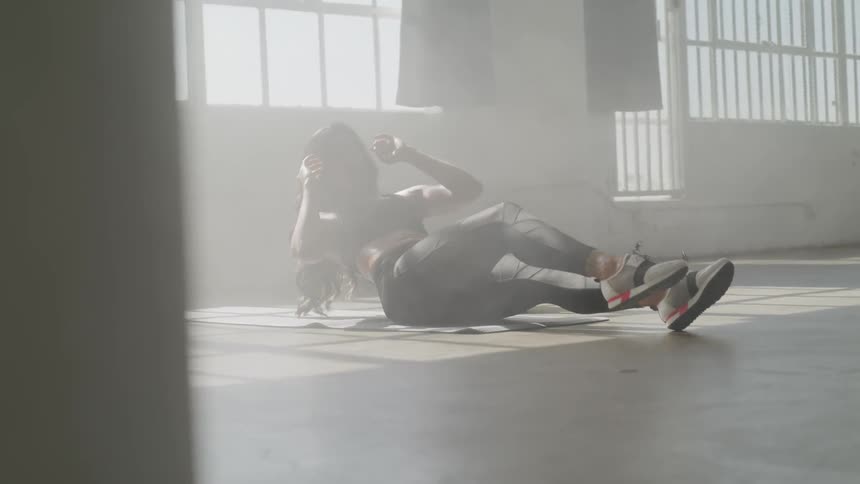 A woman does sit ups in an empty room