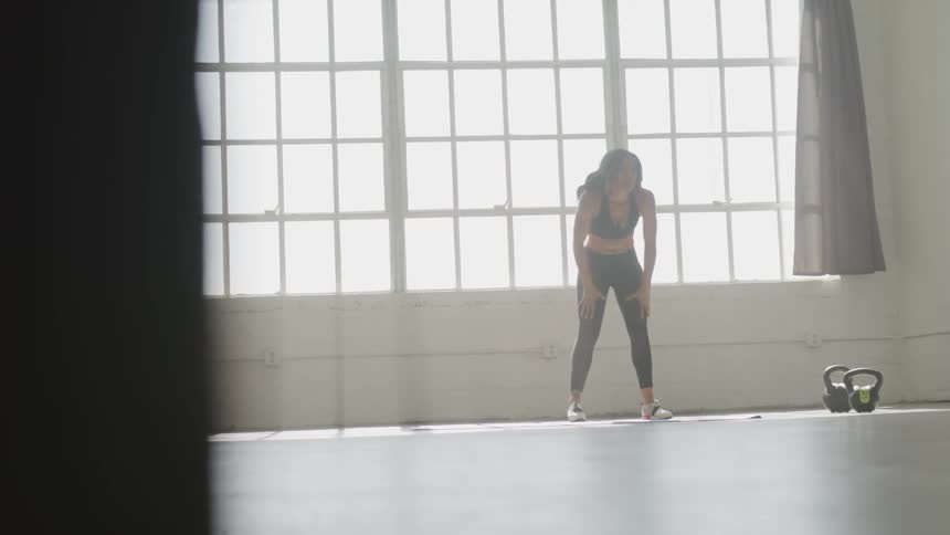 Brunette woman has a break during workout in front of arched window by day