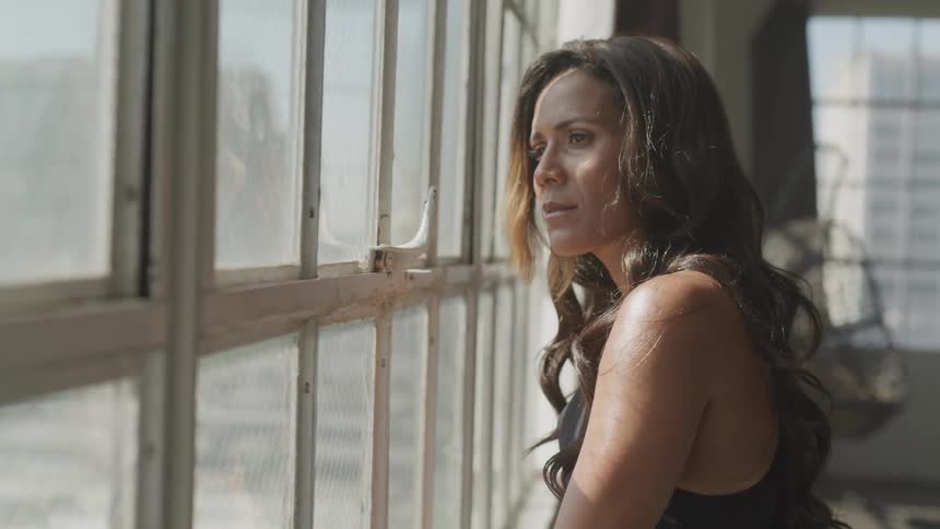 A woman looks out of a large window