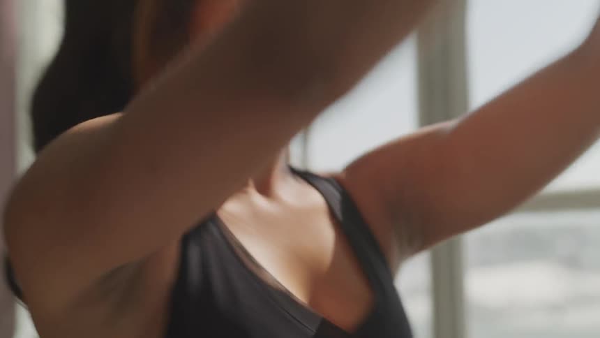 A woman squats and lifts her arms above her head