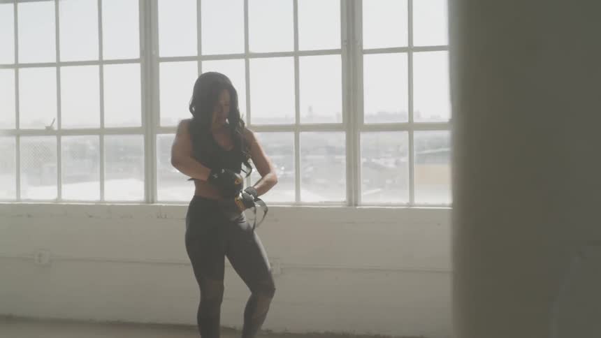 A woman puts boxing gloves on