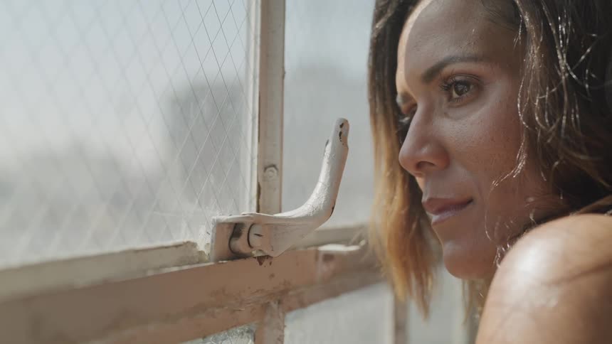 Sad brunette woman looking outside a window nervously