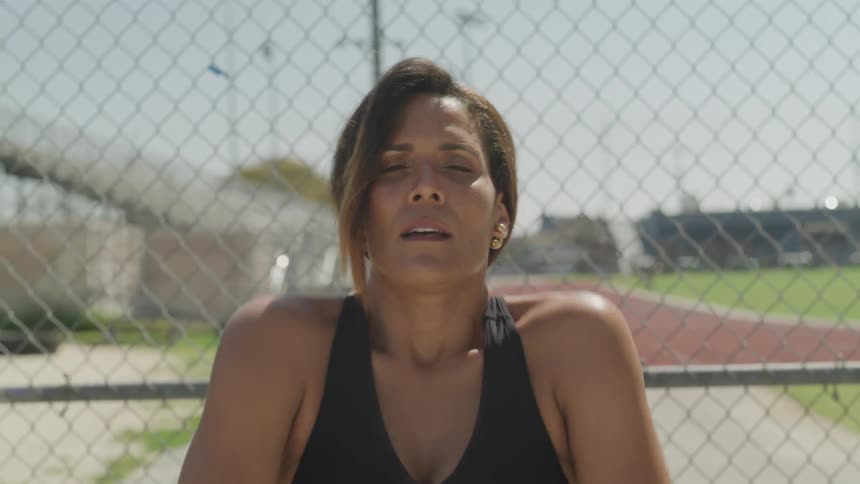 A woman stretches in front of a track