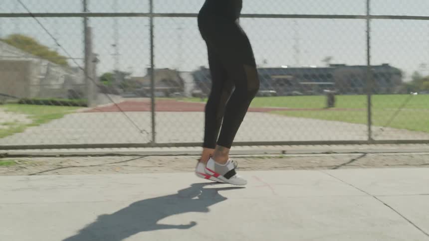 Woman warms up and starts runningnext to wire fence during daylight