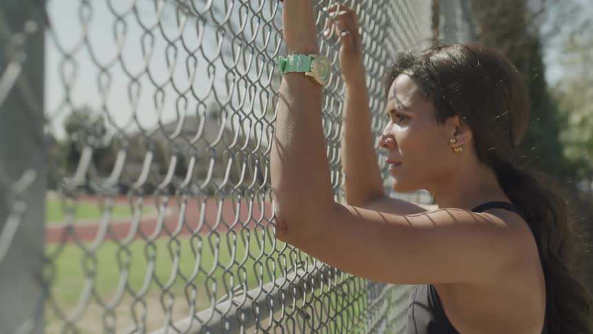 A woman stands against a fence