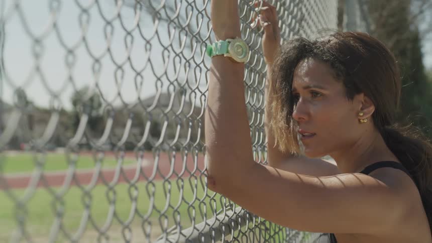 A woman is holding onto a fence looking worried