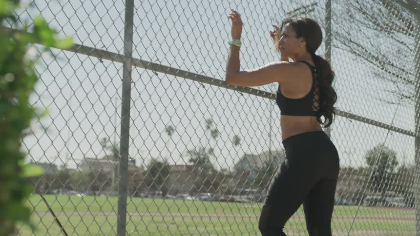 A woman stands against a fence