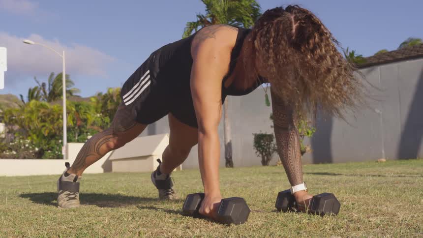 A woman is doing pushups on barbells