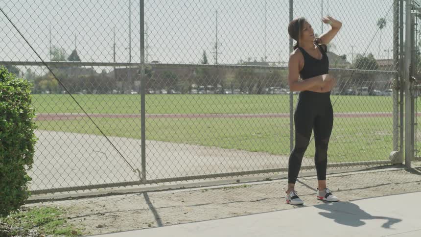 A woman stretches her muscles outside of a running track