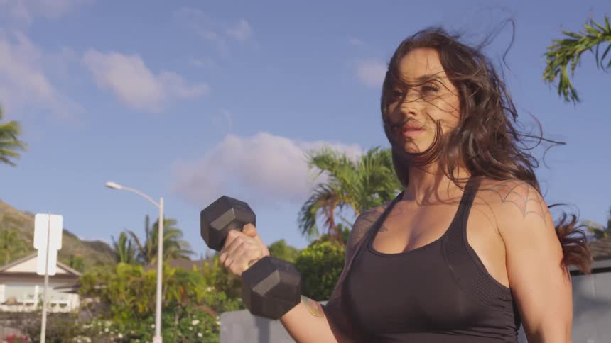 Woman lifts dumbbells outdoors on a windy day