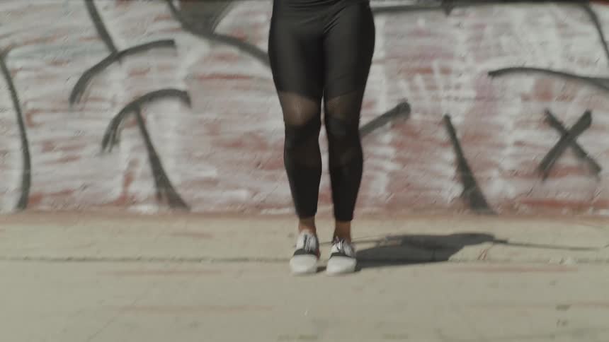 A young black woman jumps rope outside