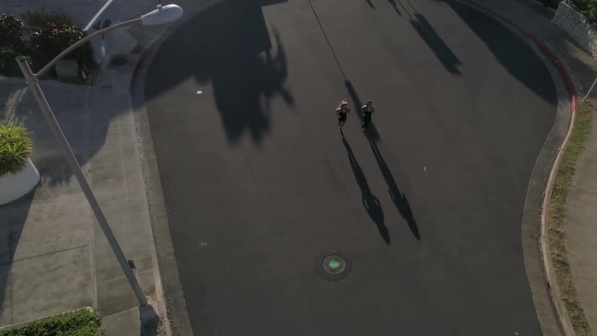 Two women run through a cul de sac