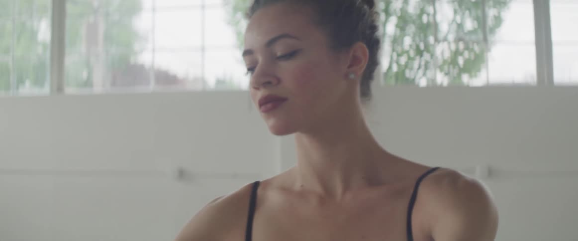A dancer stands up and leans backwards stretching her body and rehearsing