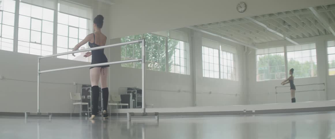Woman practices ballet in a large room