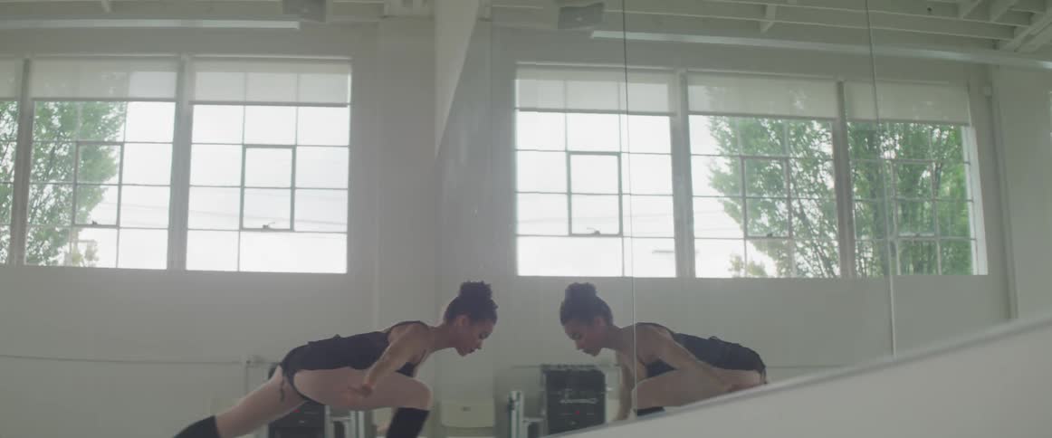 A woman practices dance moves in front of a mirror