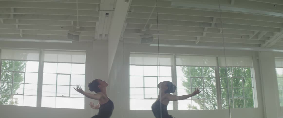 A woman dances in front of a mirror