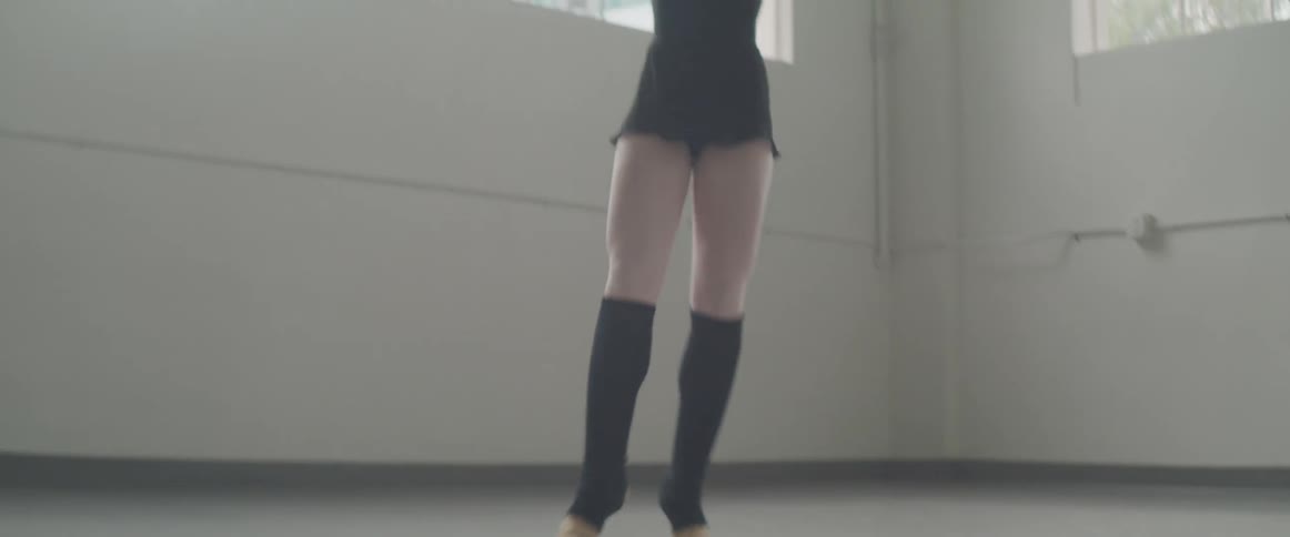 Ballerina dances in a room during daylight