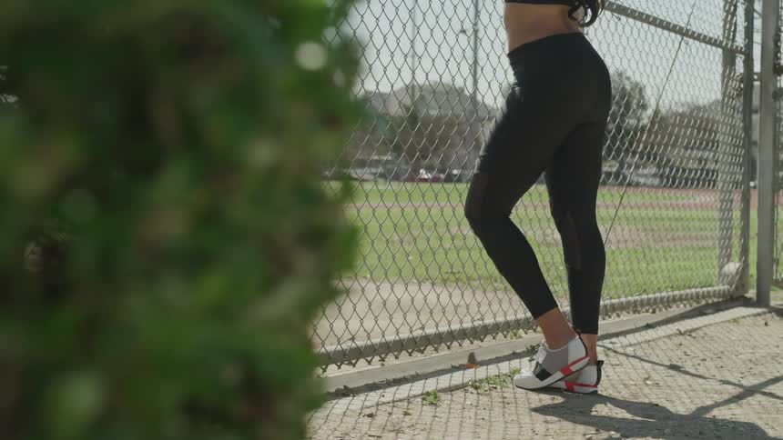 A woman stands against a fence