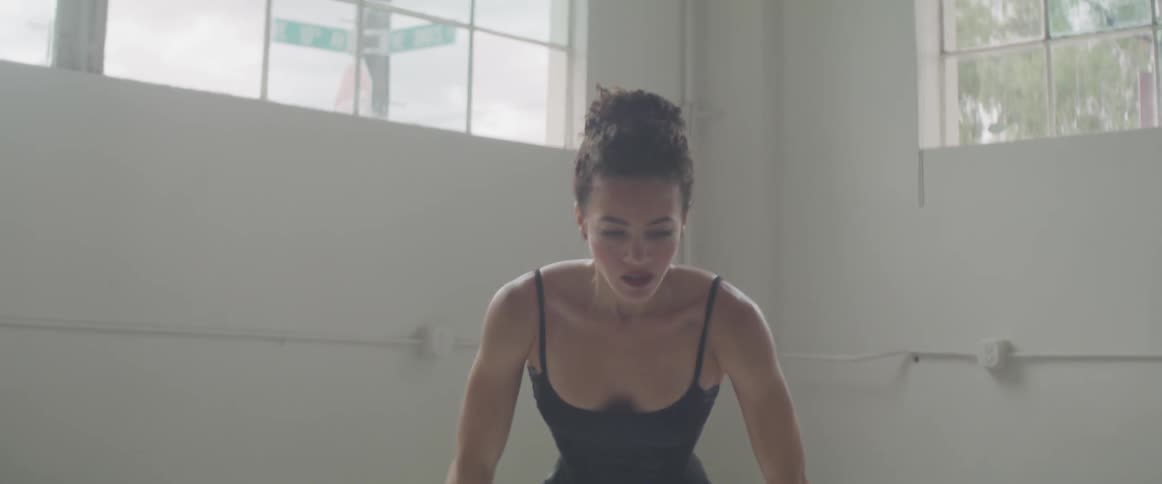 A dancer doing stretches in a studio with white walls