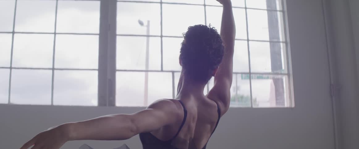 Ballerina dancing in the hall next to a big window