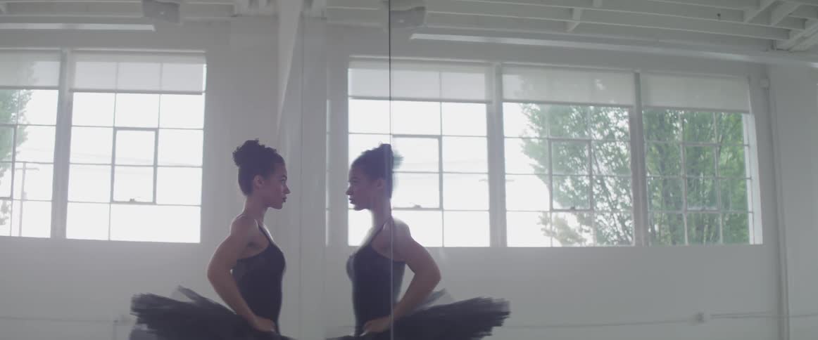 A woman stares into a mirror on the wall of a fitness studio