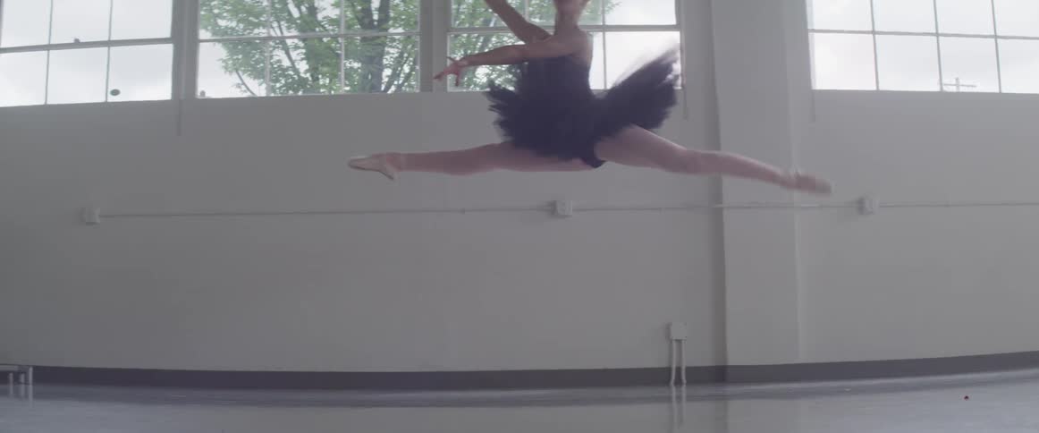 A ballerina jumps in the air dancing