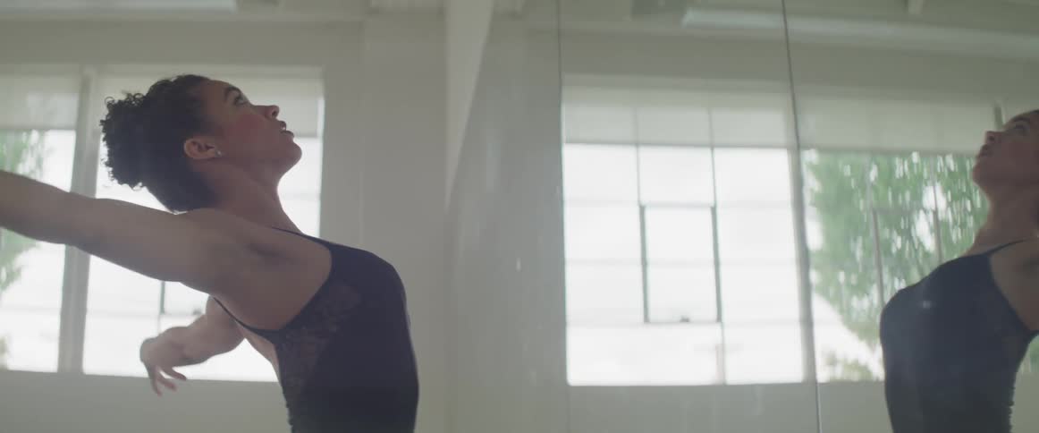 A ballerina dances in front of a mirror