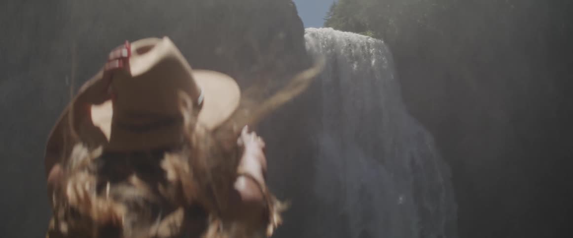 A woman stares at a roaring waterfall