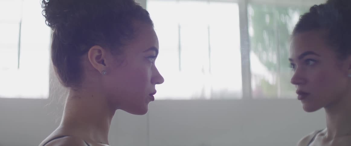 Woman stands staring at her own reflection