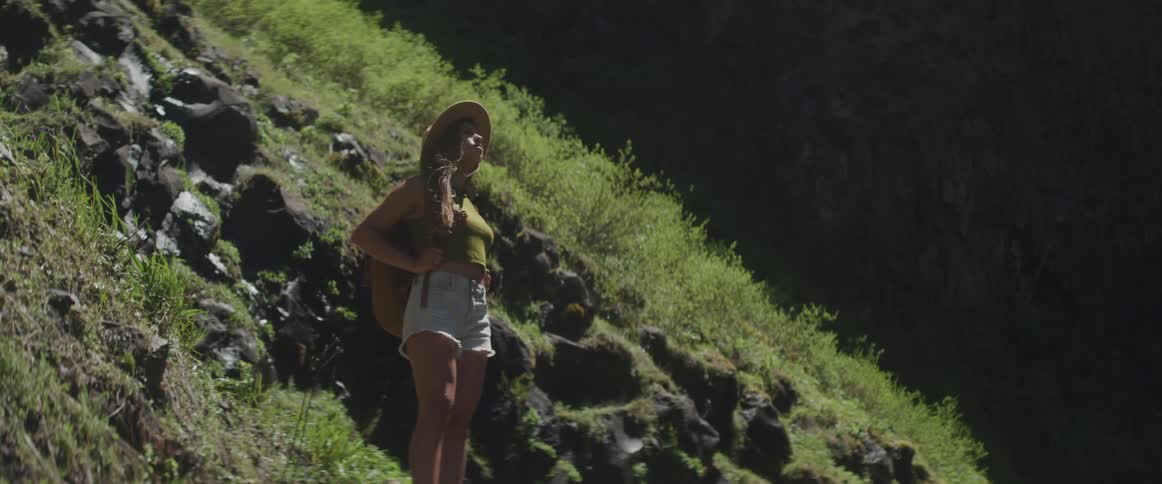 A woman in denim shorts takes in the sun on a hillside location