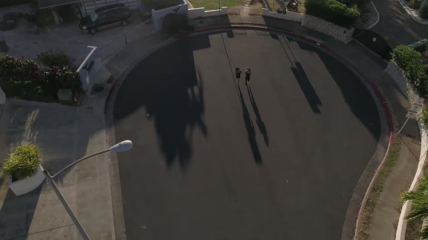 A birds eye view of two females jogging on a cul de sac