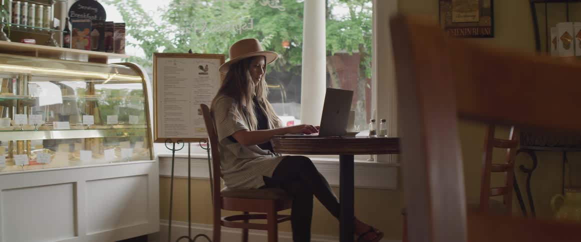 A woman typing on a laptop at a table in a cafe